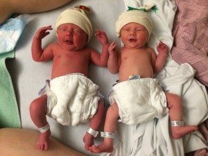 twin infants in diapers and hats