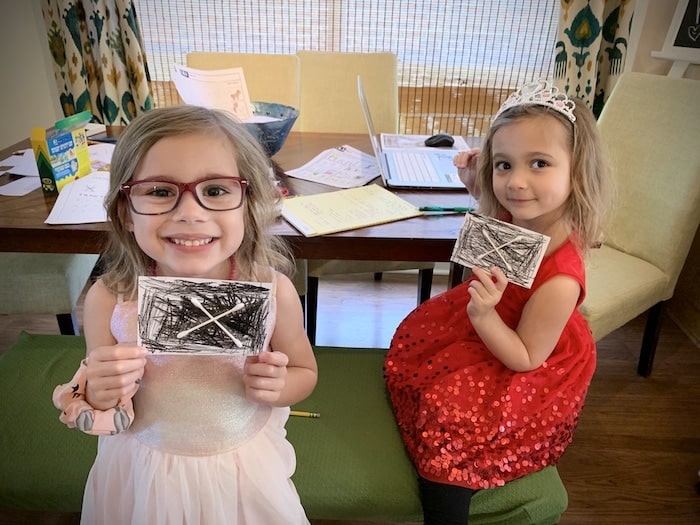 twin girls holding up an art project during a pandemic