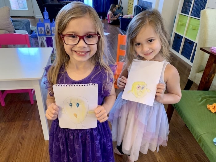 twin girls holding up drawings during a pandemic