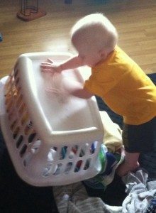 a toddler dumping a laundry basket onto a floor