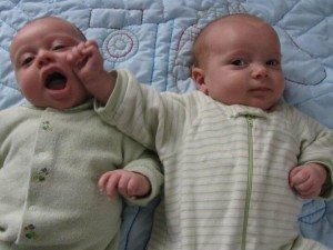 one infant twin trying to each toher others hand
