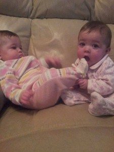 one infants putting anothers foot in their mouth on a counch